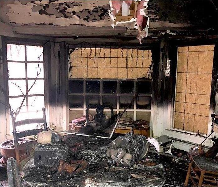Inside residential fire damage with board-up windows for security